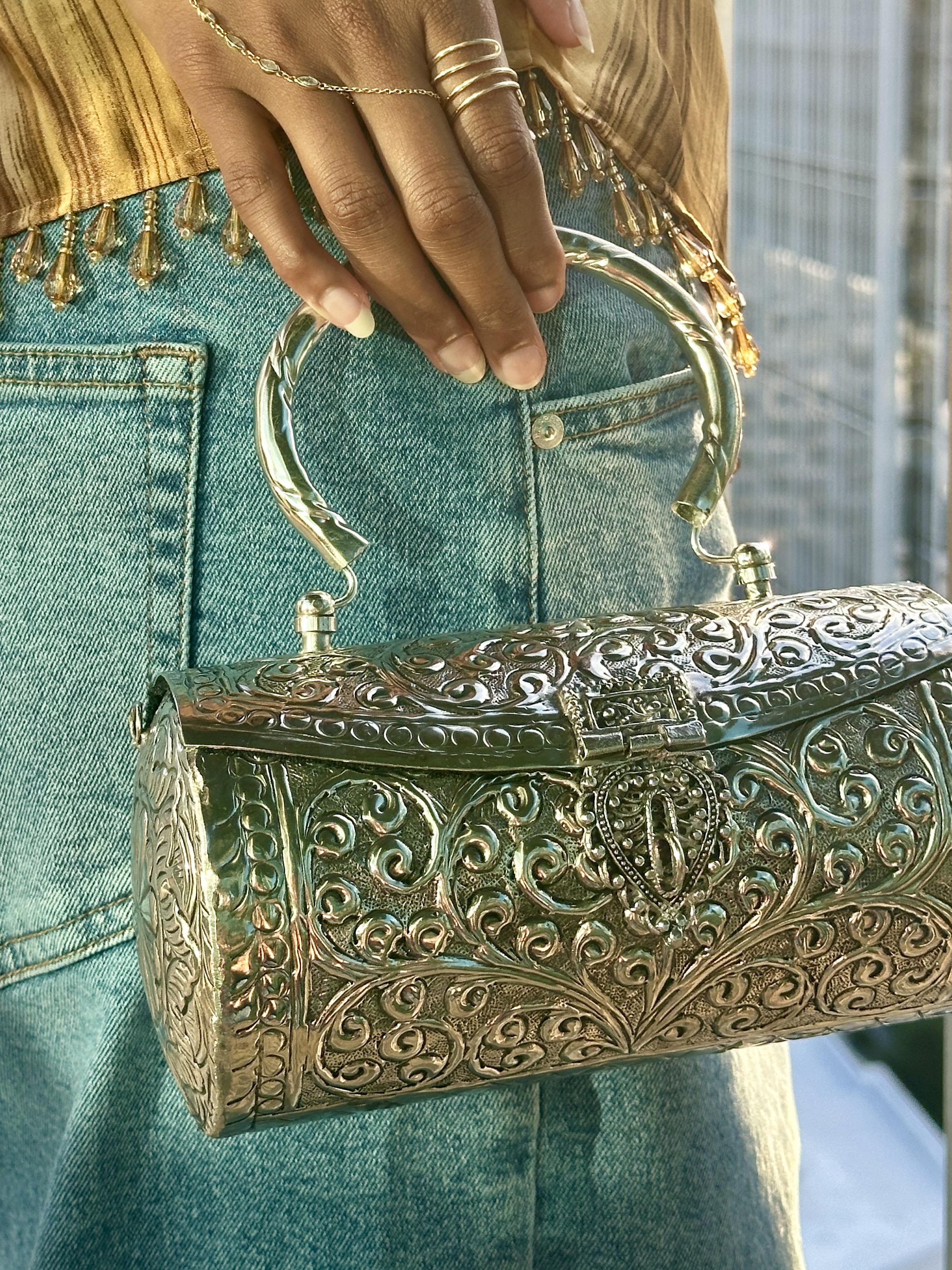 Hand carrying a handcrafted VARNA silver clutch against a city skyline